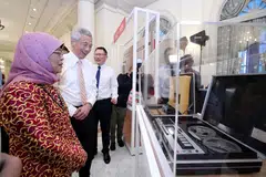 LIHAT PAMERAN: Presiden Halimah disertai Encik Lee semasa melihat pameran yang menyorot sejarah dan perkembangan CPIB sempena ulang tahun ke-70 biro itu pada Rabu malam. - Foto BH oleh DESMOND WEE 