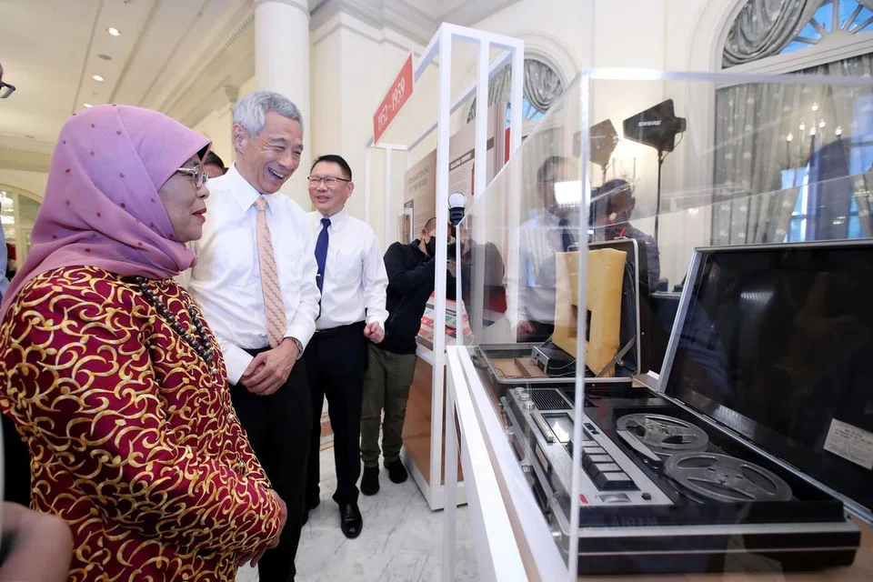 LIHAT PAMERAN: Presiden Halimah disertai Encik Lee semasa melihat pameran yang menyorot sejarah dan perkembangan CPIB sempena ulang tahun ke-70 biro itu pada Rabu malam. - Foto BH oleh DESMOND WEE 