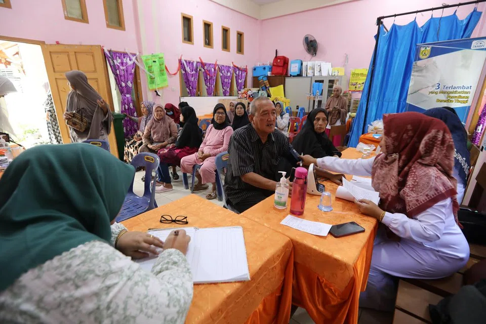 TINGKAT KEWASPADAAN: Petugas kesihatan menjalankan pemeriksaan kesihatan warga emas di Pusat Kesihatan Masyarakat di Banda Aceh, Indonesia sejajar kempen mencegah penyakit berjangkit dan meningkatkan mutu hidup warga emas. .