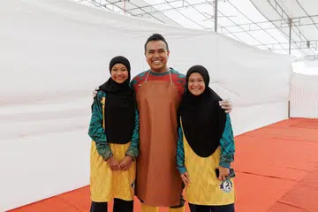 Anggota Parlimen (MP) GRC Pasir Ris-Changi, Encik Sharael Taha (tengah), 44 tahun, bertindak sebagai salah seorang penyembelih sukarelawan di operasi korban di pekarangan Masjid Al-Istighfar pada 27 Mei, bersama keluarganya. Gandingan keluarga itu menyaksikan anak lelakinya, Mohamed Zafir Iman (tiada dalam gambar), 11 tahun, bertindak sebagai pengendali haiwan, manakala isterinya, Cik Noreen Azli (tiada dalam gambar), 41 tahun, bersama dua anak perempuan mereka, Marsya Nayli (kanan), 18 tahun , dan Sarah Naimah (kiri), 14 tahun, memastikan kelancaran urusan di bahagian pentadbiran masjid dan pergerakan sohibul korban.