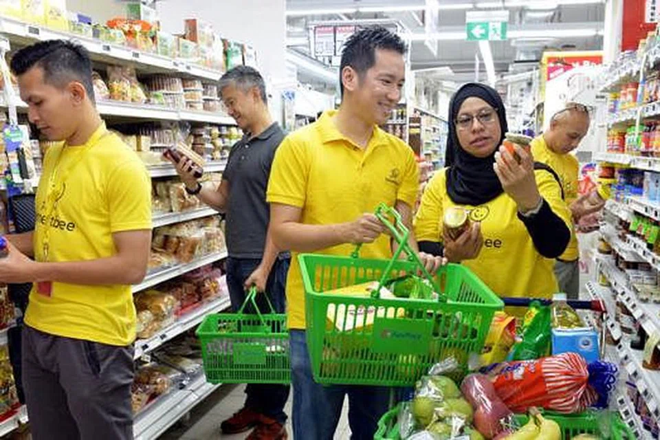 BELI-BELAH, DAPAT PENDAPATAN: Cik Malikah bersama Encik Isaac Tay (tiga dari kiri) serta kakitangan Honestbee yang lain sedang melihat barang makanan dalam tin yang ingin dibeli di cawangan FairPrice di Sun Plaza. - Foto M.0. SALLEH