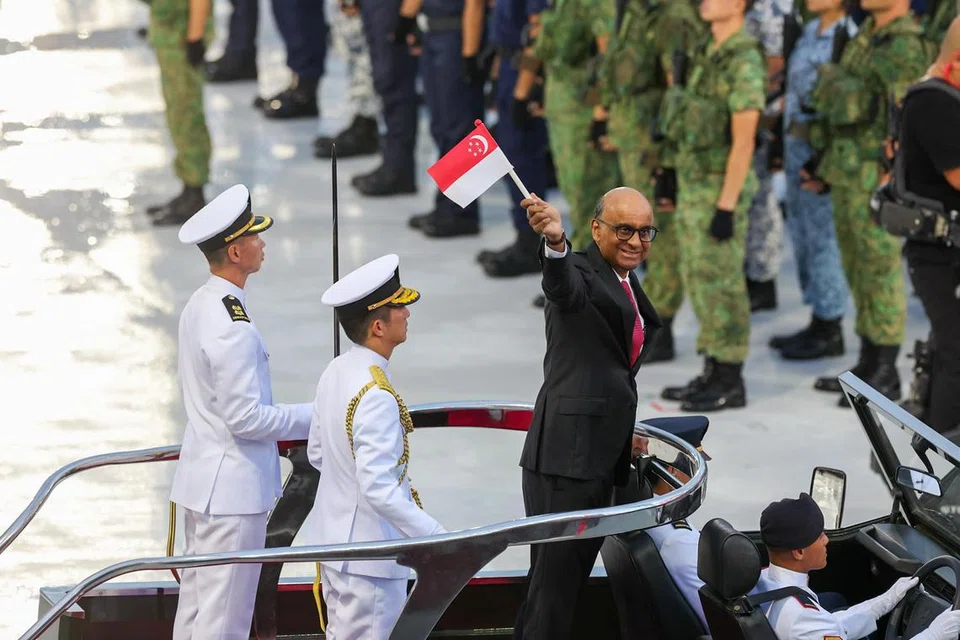 Presiden Tharman Shanmugaratnam (kanan) melambai kepada penonton di Padang selepas memeriksa Kawalan Kehormatan dan kontinjen pembawa panji-panji.