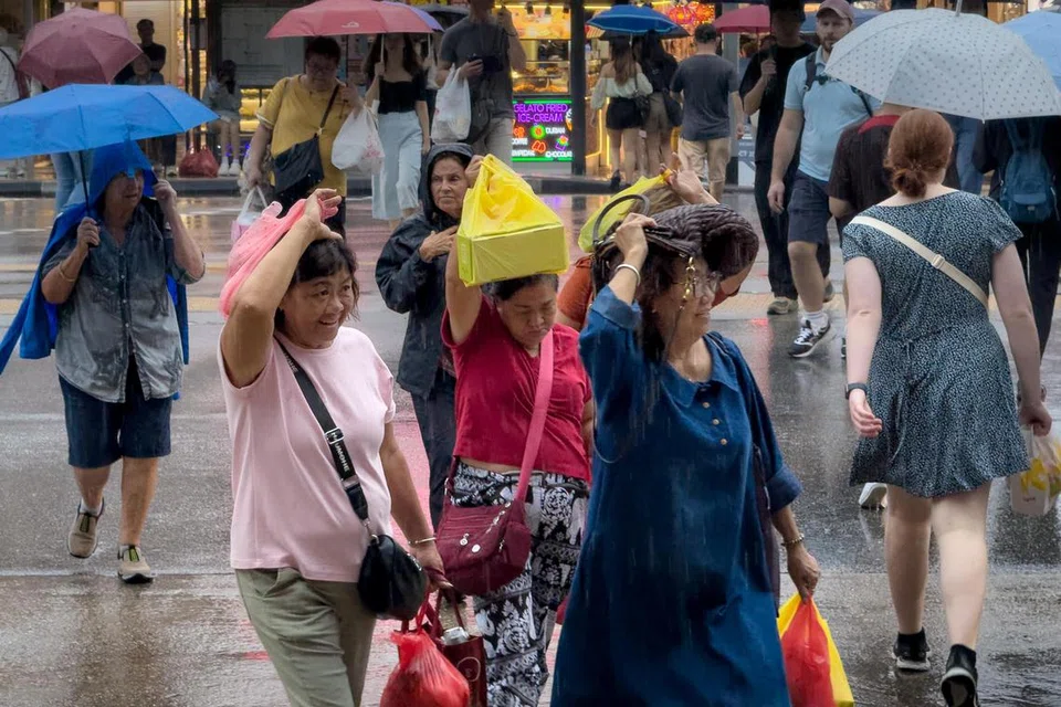 Pejalan kaki menyeberangi Victoria Street di persimpangan trafik dalam keadaan hujan lebat pada 10 Januari.