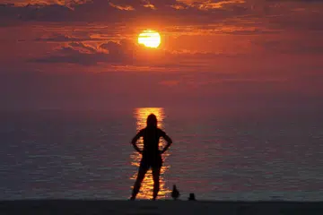 Seorang wanita menyaksikan terbitnya matahari fajar di Rehoboth Beach, Delaware, Amerika Syarikat pada August 29 lalu. 