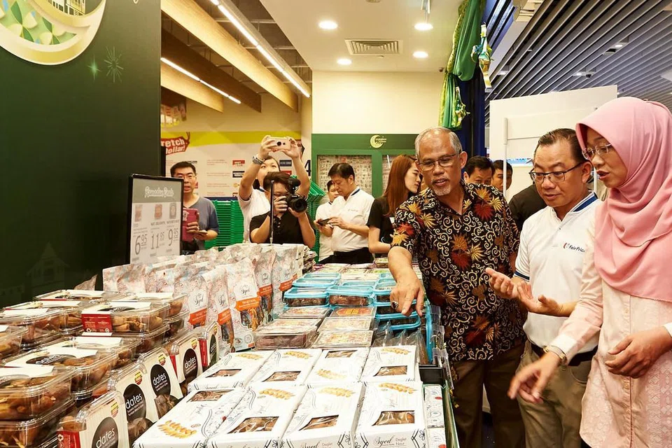 HARGAI SUMBANGAN: Encik Masagos (tiga dari kanan) berasa kagum dengan pelbagai jenis kurma yang kini dijual di NTUC FairPrice sambil disaksikan Encik Seah (dua dari kanan) dan Cik Rahayu (kanan). - Foto BH oleh ROSLEE ABDUL RAZAK