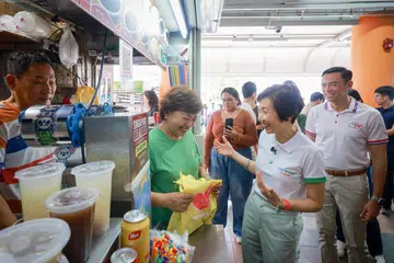 Menteri Kemampanan dan Sekitaran, Cik Grace Fu (dua dari kanan) dan Anggota Parlimen GRC Jalan Besar, Dr Wan Rizal Wan Zakariah (kanan) bertemu dengan para penjaja sambil mengagihkan pek bantuan di Pasar Beo Crescent pada 22 Oktober.