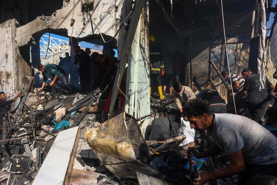 Para penduduk Palestin memeriksa bangunan yang musnah akibat pengeboman Israel ke atas Kem Pelarian Maghazi di Gaza pada 24 Oktober.