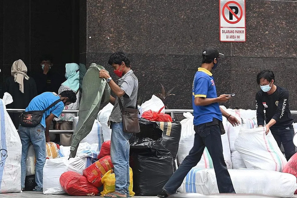 PAKAI PELITUP: Penduduk di Jakarta dilihat memakai pelitup semasa berada di luar sebuah pasar di ibu kota Indonesia itu. - AFP