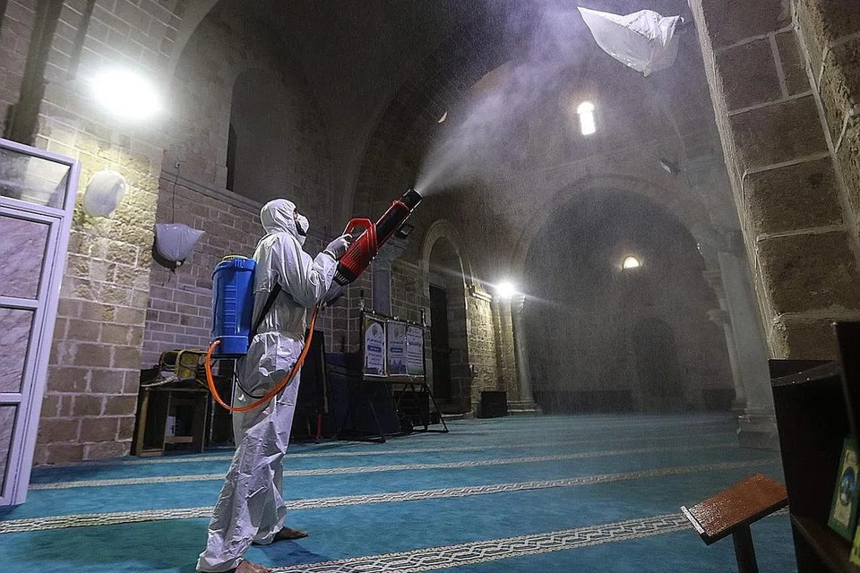 BERSIHKAN MASJID: Pekerja Palestin (gambar atas) dengan pakaian perlidungan menyahjangkit tembok di dalam Masjid Al-Omari sebagai langkah pencegahan mengekang penularan Covid-19. Para pekerja yang sama solat sebentar selepas menjalankan kerja pembersihan. - Foto AFP