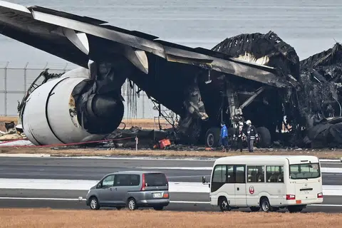 HANGUS: Para pegawai menyiasat bangkai pesawat Japan Airlines yang hangus, di lapangan terbang antarabangsa Tokyo, Haneda pada 3 Januari setelah berlanggar dengan pesawat kecil pengawal pantai. Lima orang dalam pesawat kecil itu terbunuh.  