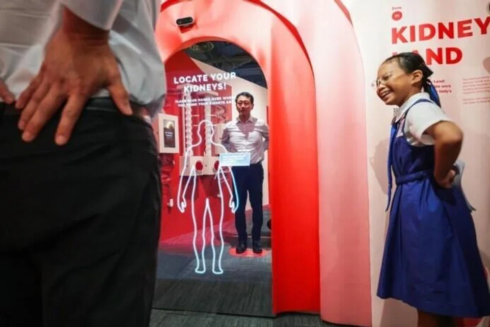 Menteri Penyelaras bagi Dasar Sosial merangkap Menteri Kesihatan, Encik Ong Ye Kun (kiri), mendengar penjelasan tentang kedudukan buah pinggang kita daripada Rachel Loy, seorang pelajar dari CHIJ Our Lady of Good Counsel, semasa lawatannya ke Pusat Penerokaan Buah Pinggang NKF di pusat NKF baru di Kim Keat pada 23 Mac.