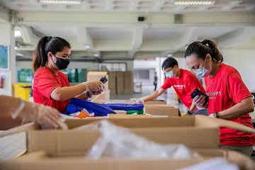 BELIA BERTINDAK: Sukarelawan daripada Pasukan Belia Singapura menyingsing lengan bagi menyiapkan bungkusan habuan untuk diagihkan kepada pekerja migran, sempena sambutan Hari Kebangsaan 2021 dan Hari Migran Antarabangsa 2021. - Foto-foto MAJLIS BELIA KEBANGSAAN (NYC) 