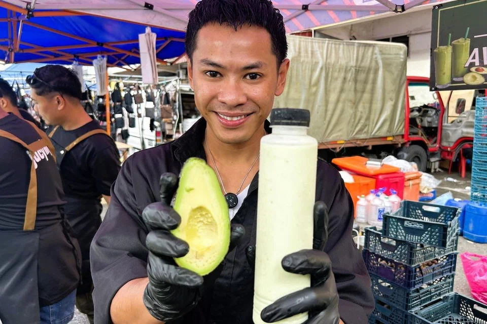 Razzuan menunjukkan buah avocado dan jus avocado yang dijual di gerai milik ayahnya di Johor Jaya, Johor Bahru.