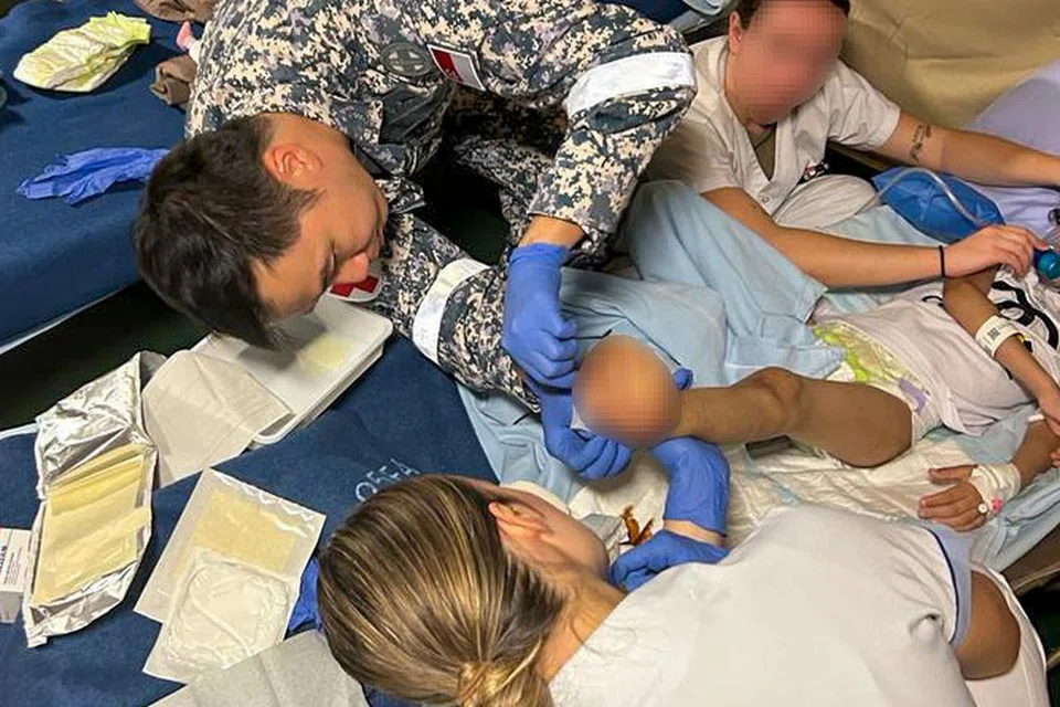 LAKSANA MISI KEMANUSIAAN: Pakar Tentera 3 (ME3) Jimmy Woo Ying Ming (pertama dari kiri) membersihkan dan membalut luka untuk pesakit.