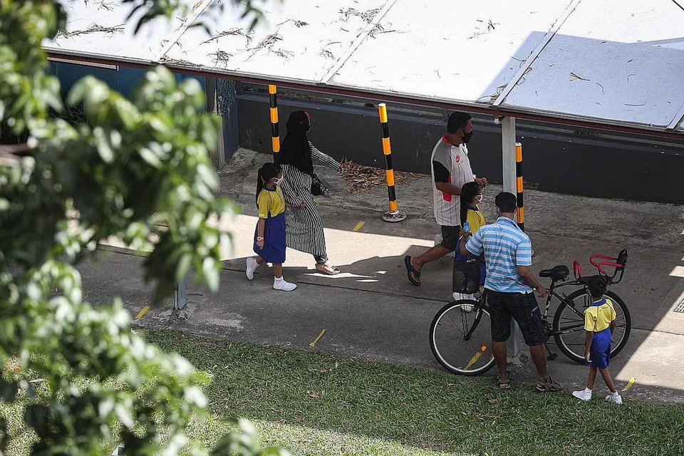 UJIAN WAJIB: Murid Sekolah Rendah Punggol semalam datang ke sekolah untuk menjalani ujian swab Covid-19. - Foto ZAOBAO
