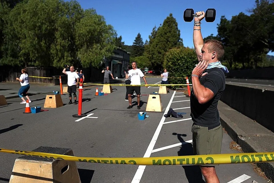 JAGA KESIHATAN DAN KECERGASAN: Seorang anggota gimnasium bersenam di luar sambil memegang dumbel serta mengamalkan jarak selamat di San Anselmo, California memandangkan gimnasium dan jalan raya di bandar San Anselmo ditutup. - Foto AFP