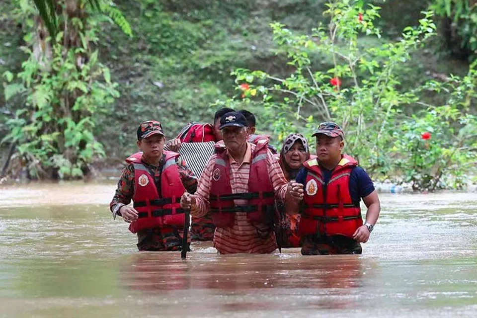 DILANDA BANJIR: Anggota Bomba dan Penyelamat membantu beberapa warga meredah banjir untuk dipindahkan ke PPS selepas rumah mereka terputus hubungan akibat banjir di Kampung Rancangan Cocos, Beluran, Sabah.