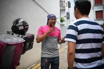 BERBUAL MENERUSI BAHASA ISYARAT: Cabaran utama yang dihadapi penghantar makanan pekak sepertinya, kata Encik Rizal, adalah berkomunikasi dengan pelanggan, pemilik dan pekerja restoran dan kadangkala pegawai keselamatan apabila beliau menghantar makanan ke kondominium atau pejabat. - Foto BM oleh MARK CHEONG