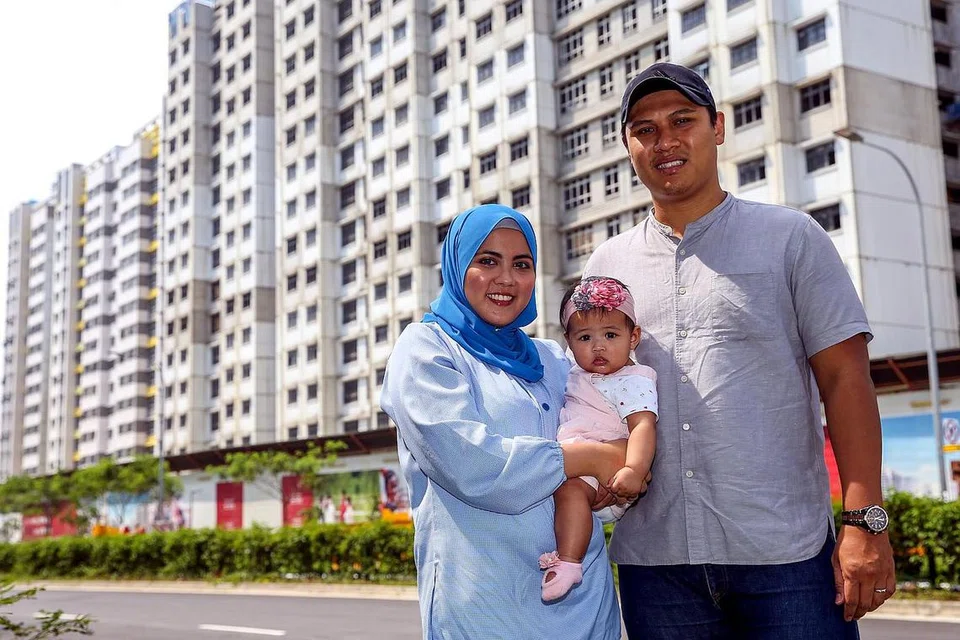 TERTANGGUH LAGI: Cik Nurafiqah Daud dan suami, Encik Muhammad Audi Mohamed Rathi, serta anak mereka, Nur Aisha Muhammad Audi, bergambar di hadapan tapak binaan BTO Tampines GreenCourt. Mereka sepatutnya berpindah ke rumah baru mereka pada suku pertama 2022. - Foto fail