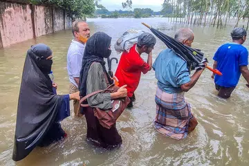 Residents wade through floodwaters after heavy monsoon rains in Chattogram on July 12, 2026. Flash floods triggered by an active monsoon affecting parts of India and Bangladesh have killed 50 people in Bangladesh's Chattogram Division over the past week, the government said. (Photo by Rabin Chowdhury / AFP)
