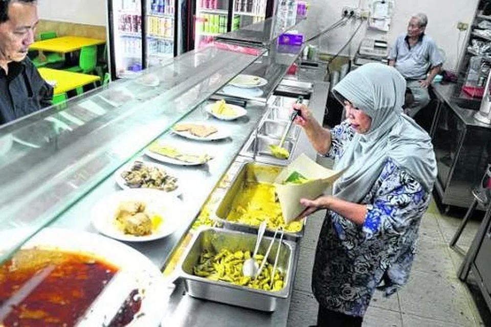 NIKMATI HIDANGAN SEBELUM DITUTUP: Seorang pelanggan (kiri) kedai Nasi Padang River Valley, yang bakal ditutup pada 28 Mac, ketika dilayani seorang pekerja, Cik Liza Ahmad. - Foto THE STRAITS TIMES