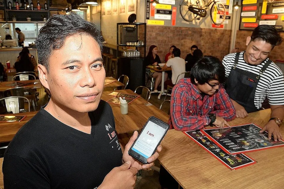 MUDAH DAN CEPAT: Encik Jamuri (depan) menunjukkan aplikasi yang membolehkan pelanggan menempah makanan dan membuat bayaran menggunakan telefon bimbit mereka sendiri. - Foto JOHARI RAHMAT