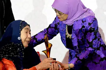 TERIMA ANUGERAH DARI PRESIDEN: Presiden Halimah Yacob (bertudung ungu) menyampaikan anugerah piala Dewan Termasyhur Wanita Singapura (SWHF) kepada Puan Noor Aishah, yang disenaraikan dalam SWHF dalam satu majlis kelmarin. - Foto BH oleh KHALID BABA