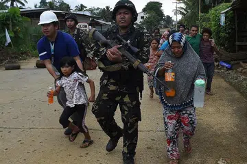 BANTU PENDUDUK KAMPUNG: Askar Filipina membantu penduduk kampung berpindah daripada tempat tinggal mereka di pinggir bandar Marawi ke tempat selamat ketika pertempuran antara tentera negara itu dengan kumpulan militan masih berterusan. - Foto AFP