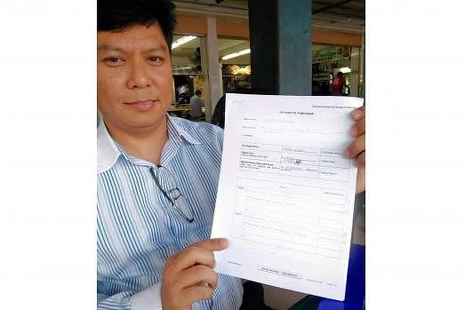 BAYARAN OPSYEN BELI RUMAH RENDAH: Encik Hamzah menunjukkan borang opsyen untuk membeli dengan bayaran hanya $100 yang dibayar pelanggannya untuk membeli flat lebih besar di Woodlands. - Foto SAINI SALLEH