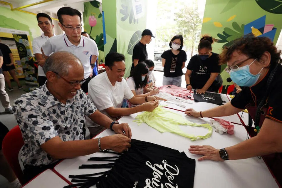 USAHA MENGHIJAU: Menteri Pembangunan Sosial dan Keluarga, Encik Masagos Zulkifli Masagos Mohamad (duduk, kiri) dan Anggota Parlimen GRC Jalan Besar, Dr Wan Rizal Wan Zakariah (duduk, dua dari kiri) belajar cara membuat beg beli-belah menggunakan kemeja-T terpakai di Blok 68 Geylang Bahru,pada 3 Disember. 