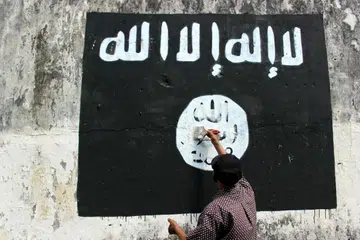 TOLAK KEHADIRAN ISIS: Seorang penduduk di Jawa Tengah mengecat bagi memadamkan bendera IS yang dilukis penyokong tegar kumpulan militan tersebut di bandar itu. - Foto TEMPO