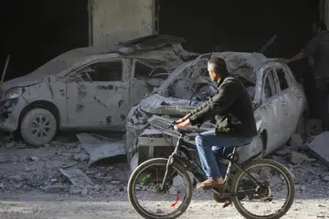 SEMAKIN MUSNAH: Seorang lelaki Palestin mengayuh basikal sambil melihat kereta-kereta dan bangunan yang musnah akibat pengeboman Israel di bandar Al-Balah, selatan Gaza, pada 7 Januari.
