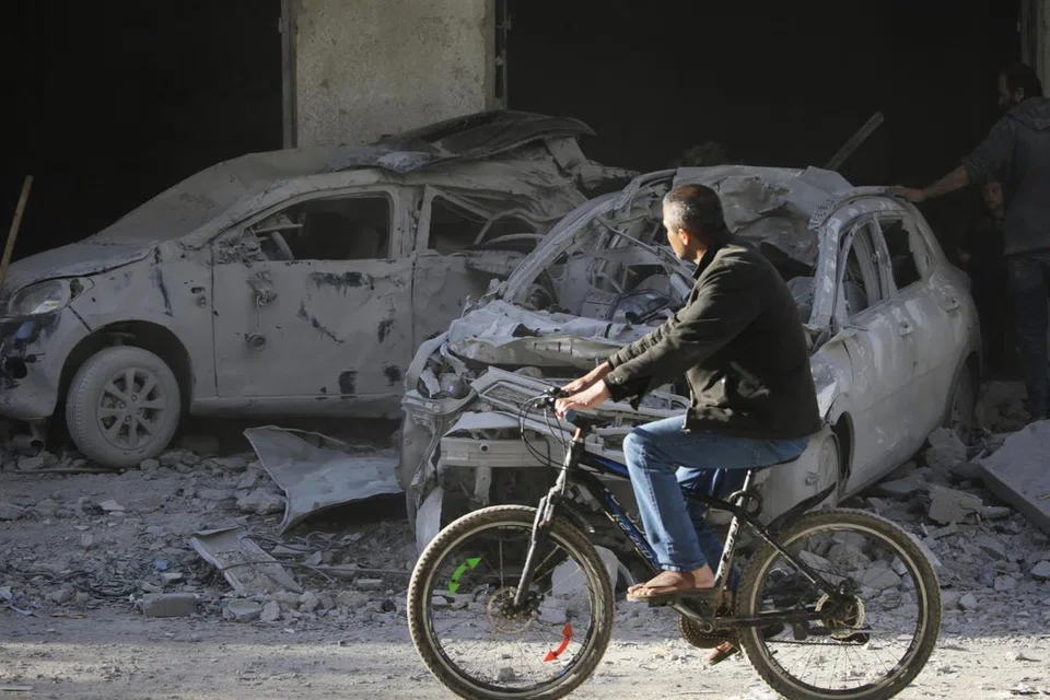 SEMAKIN MUSNAH: Seorang lelaki Palestin mengayuh basikal sambil melihat kereta-kereta dan bangunan yang musnah akibat pengeboman Israel di bandar Al-Balah, selatan Gaza, pada 7 Januari.