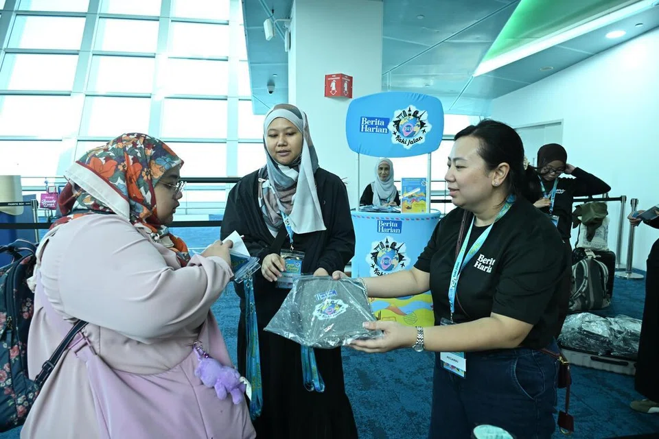 Peserta menerima lanyard serta beg galas ketika mendaftar masuk kapal persiaran.