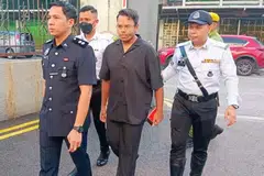 Muhammad Irsyad Abdul Hameed (dua dari kanan) diiringi polis ketika tiba di Mahkamah Majistret Johor Bahru pada 15 Mei.