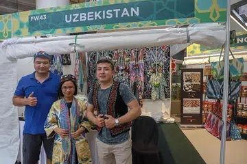 INGIN BERKONGSI: Encik Damir (kiri) dan rakannya, Encik Magrurjon Ergasher (kanan) ingin berkongsi makanan dan pakaian tradisional mereka dari Uzbekistan. Penulis, Sri Afiqah Hamir (tengah) berpeluang mencuba pakaian Uzbekistan yang lengkap dengan songkoknya. Pakaian yang dikenakan wartawan dan jaket Encik Magrurjon juga sesuai untuk dikenakan pada Hari Raya nanti. - Foto BH oleh IQBAL FAIIZAL