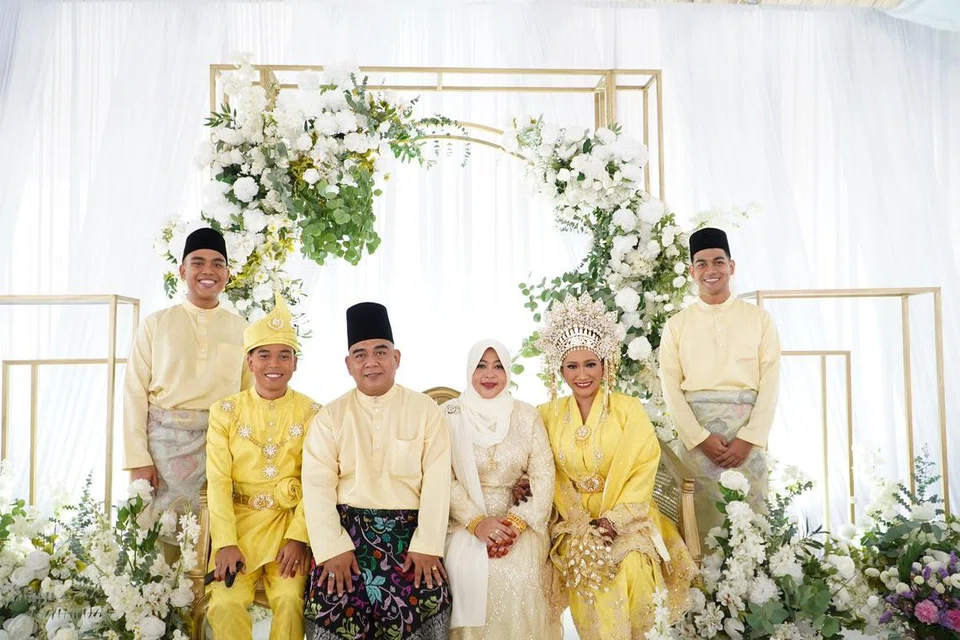 BERGAMBAR BERKELUARGA: Pengantin baru, Encik Nazran Zaiyani Ahmad Jufri, 26 tahun dan Cik Nor Natisha Yusoff, 24 tahun (berpakaian songket emas) bergambar bersama ayah dan ibu pengantin lelaki, Encik Ahmad Jufri Ahmad Jupar, 52 tahun dan Cik Haslini Abdul Jaman, 50 tahun (tengah) bersama adik Encik Nazran, Encik Nazir Zuhri, 21 tahun (paling kanan) dan Encik Nabil Zikry, 22 tahun (paling kiri).