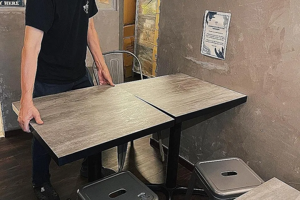 SIAP SEDIA TERIMA PELANGGAN: Seorang kakitangan Kulon yang terletak di Bali Lane menyusun semula kerusi meja di restoran itu sebagai persediaan menerima pelanggan yang boleh makan di sana bermula esok. - Foto KULON