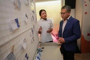 Starlett Seng, pelajar Menengah 2 dari Sekolah Menengah Peicai, memperkenalkan paparan interaktif mengenai cara menangani gangguan dalam talian kepada Menteri Undang-Undang merangkap Menteri Kedua (Ehwal Dalam Negeri), Encik Edwin Tong, di Pusat SHECARES pada 24 Julai.