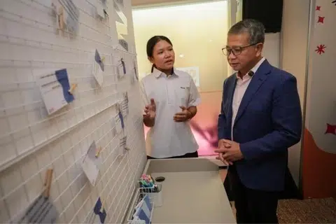 Starlett Seng, pelajar Menengah 2 dari Sekolah Menengah Peicai, memperkenalkan paparan interaktif mengenai cara menangani gangguan dalam talian kepada Menteri Undang-Undang merangkap Menteri Kedua (Ehwal Dalam Negeri), Encik Edwin Tong, di Pusat SHECARES pada 24 Julai.