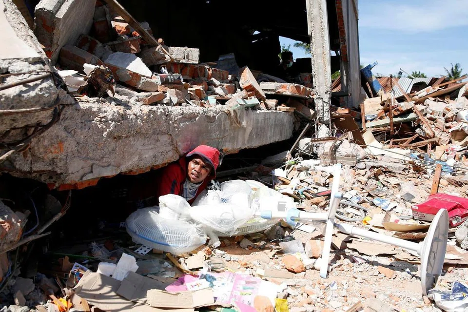 CARI MANGSA DAN HARTA BENDA: Seorang lelaki keluar daripada timbunan runtuhan bangunan di Pidie Jaya, Aceh, selepas cuba mencari mangsa yang masih hidup atau harta benda yang masih boleh diselamatkan. - Foto REUTERS