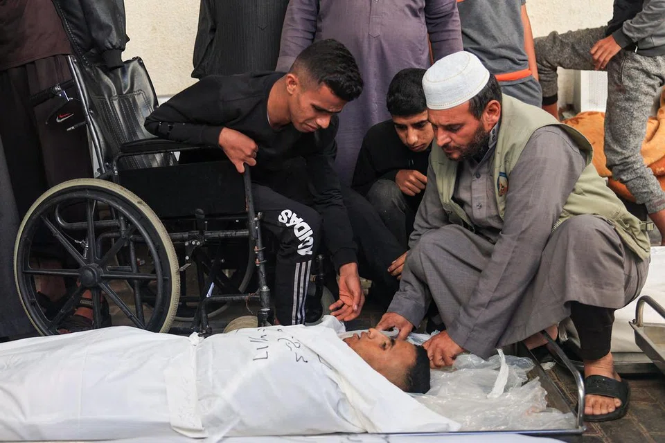 RATAPI KEMATIAN: Rakyat Palestin melihat dengan sedih kematian seorang sanak saudara mereka berikutan pengeboman Israel. 