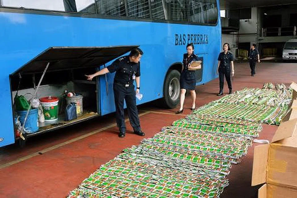 PATAHKAN PERCUBAAN SELUDUP: Pegawai ICA memeriksa sebuah bas pekerja yang cuba menyeludup tembakau tanpa cukai semalam. - Foto KHALID BABA