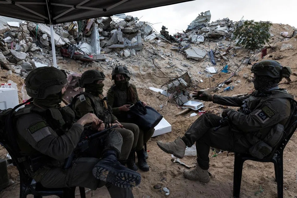 Tentera Israel duduk bersama di tengah runtuhan bangunan di Rafah, selatan Jaluran Gaza, 8 Disember 2025.