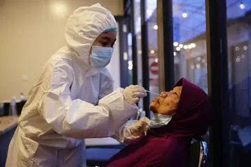 LANGKAH KESELAMATAN: Seorang pekerja jagaan kesihatan dengan sut pelindungan bahan berbahaya (Hazmat) sedang mengumpulkan sampel daripada penumpang pesawat di Lapangan Terbang Antarabangsa Soekarno-Hatta di Banten, Indonesia. - Foto EPA-EFE/ADI WEDA 