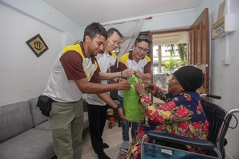 HULURKAN HABUAN: Sebagai sebahagian daripada projek amal syarikat GL Engineering & Construction, kakitangan syarikat itu (dari kiri) Syed Hassanuzzaman Omit, Encik Lim Sing Tian dan Encik Raymond Gan menghulurkan bungkusan mengandungi produk pembersihan kepada penduduk Marine Terrace, Cik Fatimah Mohd Saat. - Foto BH oleh IQBAL FAIZAL