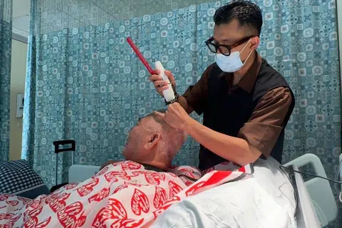 Encik Andy memotong rambut pelanggan yang merupakan pesakit angin ahmar di Hab Jagaan Bersepadu (ICH), Hospital Tan Tock Seng (TTSH). FitBarber turut menawarkan perkhidmatan kepada pelanggan yang berada di dalam hospital.