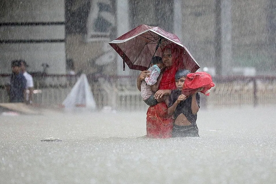 CARI TEMPAT SELAMAT: Keluarga ini dilihat meredah air banjir untuk mendapat perlindungan di bandar Sylhet yang terletak di bahagian timur laut Bangladesh. - Foto REUTERS