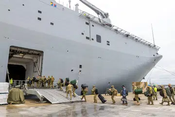 HANTAR BEKALAN BANTUAN: Askar Australia menaiki kapal HMAS Adelaide di pelabuhan Brisbane (gambar kiri) sebelum berangkat untuk menghantar bekalan bantuan ke Tonga. - Foto REUTERS