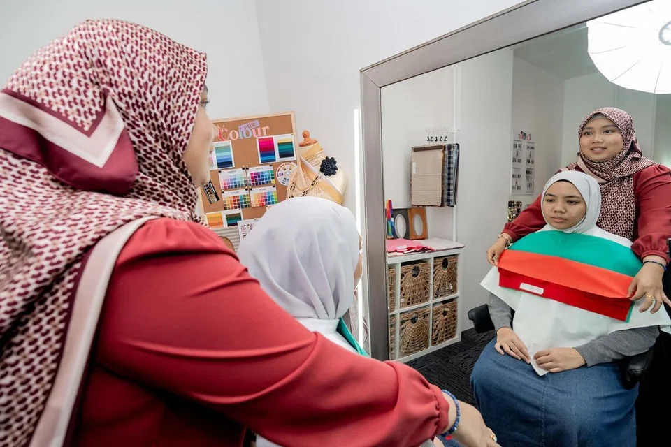 Cik Nora Anuar (kiri) meletakkan helaian kain pelbagai warna berhampiran wajah penulis, Cik Humaira Safiya Mohd Helmi, bagi mengenal pasti palet warna yang paling sesuai menerusi sesi analisis warna peribadi.